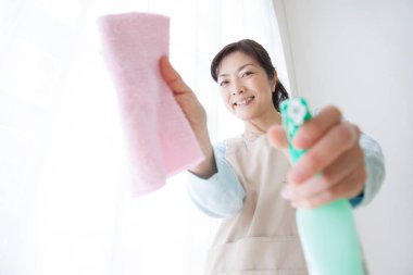 Camı bezle temizleyen Asyalı kadın.