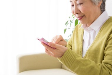 Evde akıllı telefonu olan Asyalı kadın. 