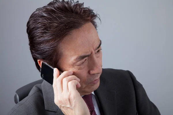 グレイを背景にした日本人ビジネスマン スマートフォンを使用して灰色のスーツのアジア人男性の肖像画 — ストック写真