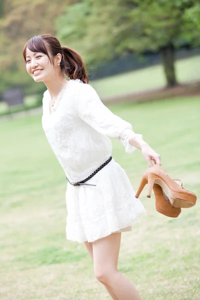 Νεαρή Γυναίκα Λευκό Φόρεμα Παπούτσια Στο Χέρι Στο Πάρκο — Φωτογραφία Αρχείου