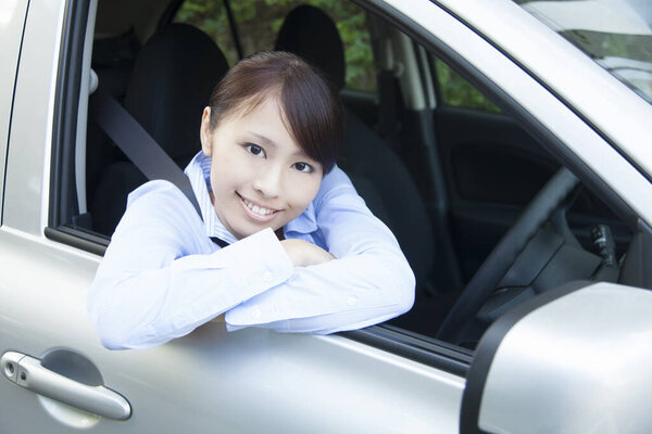 young happy asian woman sitting in car