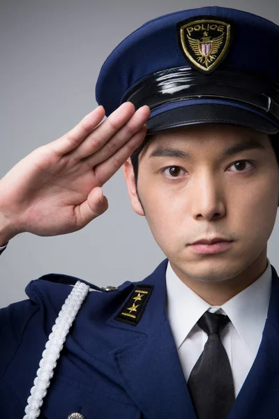 studio portrait of Japanese police officer in uniform on grey background
