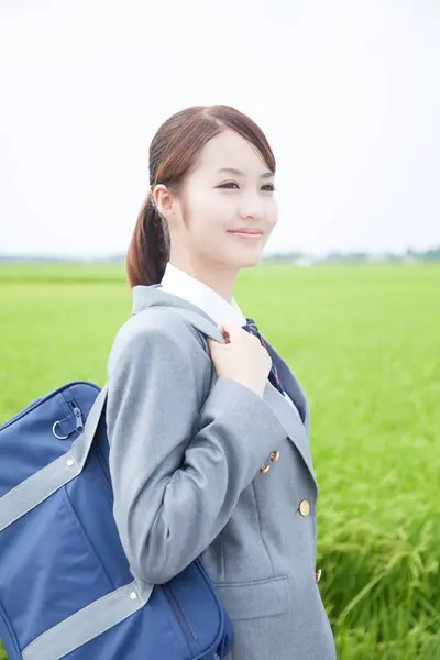 stock image smiling Asian schoolgirl walking with bag in the countryside