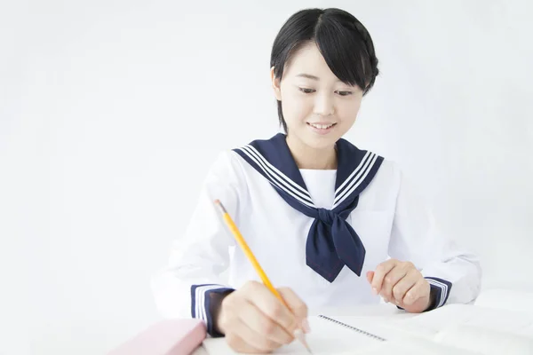 身穿校服的亚洲女孩在课桌前学习 — 图库照片