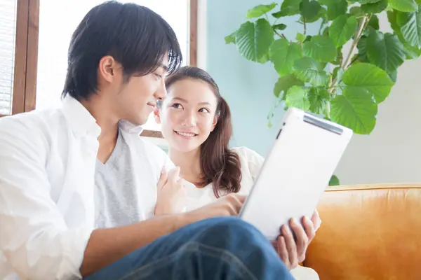 Mutlu Asyalı Adam Oturma Odasında Rahatlamak Için Tablet Bilgisayar Kullanıyor — Stok fotoğraf