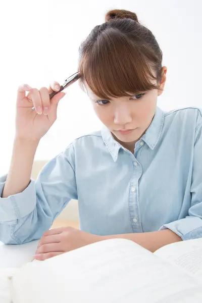 年轻的日本妇女带着书本和钢笔在家里学习 — 图库照片