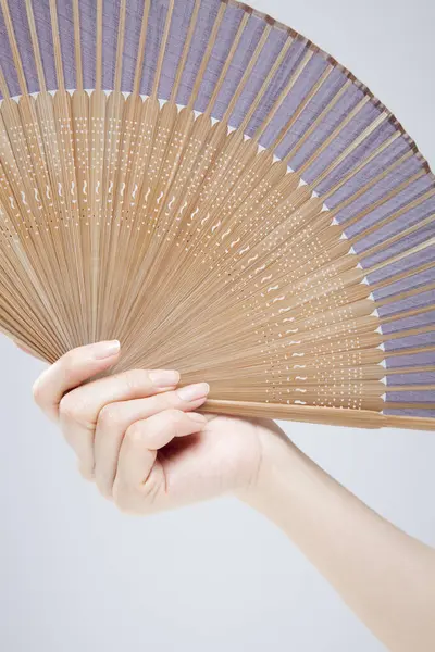 close up photo of woman holding fan in hand