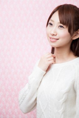 Pembe arka planda beyaz kazaklı kadın.