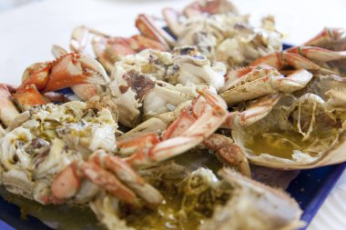 Mavi dikdörtgen tabakta servis edilen haşlanmış yengeçler.