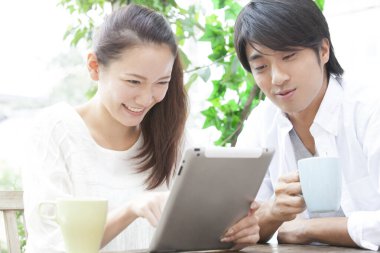 Tablet bilgisayarlı bir kafede Asyalı kadın ve erkek.