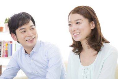 Genç Asyalı çift evde gülümsüyor.