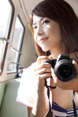 Kadın antika bir arabada retro kamerasıyla fotoğraf çekiyor..