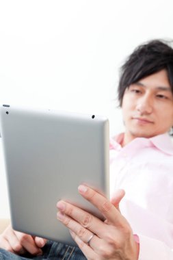 Genç Asyalı adam dijital tablet kullanıyor