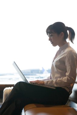 Havaalanında dizüstü bilgisayar kullanan kadın