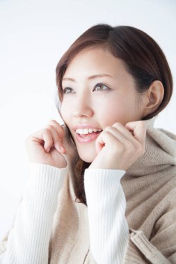 Beyaz kazak giyen genç Asyalı kadın stüdyoda poz veriyor.