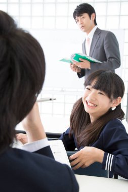 Sınıfta sınıf arkadaşıyla konuşan gülümseyen kız.