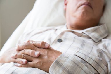 Çizgili pijama giymiş bir adam yatakta dinleniyor.