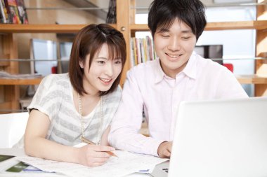 Genç Asyalı üniversite öğrencileri dizüstü bilgisayarla çalışıyorlar.