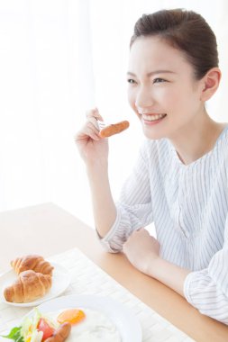 Asyalı kadın evde kahvaltı yapıyor.