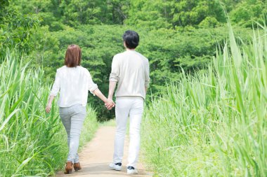 Uzun otların arasında yürüyen bir çift.