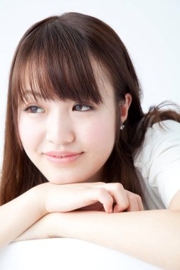 Beyaz arka planda gülümseyen Asyalı genç kadın. 