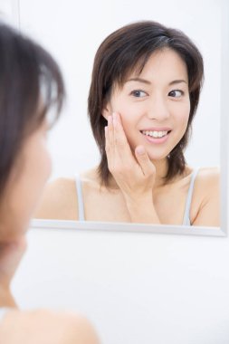 Banyodaki aynaya bakan Asyalı kadın.