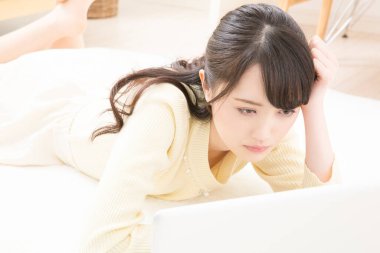 Genç Asyalı kadın dizüstü bilgisayardan bir şey izliyor ve ağlıyor.