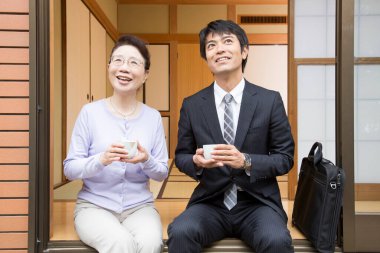 Gülümseyen adam ve kadın dışarıda oturmuş çay içiyorlar.