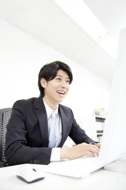 Ofiste bilgisayarla çalışan gülümseyen iş adamı 