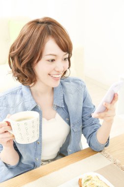 Kahve içen ve telefon kullanan güzel bir Japon kadının portresi.