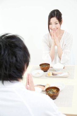 Asyalı kadın ve erkek birlikte yemek yiyorlar.