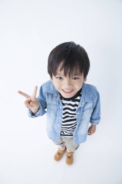 Kot ceketli Asyalı bebek zafer işareti gösteriyor.