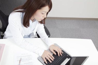 Masada dizüstü bilgisayarla çalışan Asyalı genç kadın.