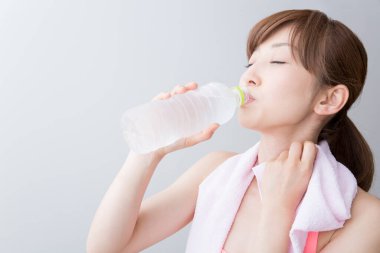 Asyalı zinde kadın su içiyor.