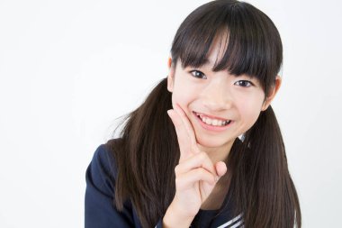 Beyaz stüdyo arka planında duran üniformalı Japon okul kızının portresi. 