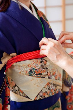 Kadın elleri, geleneksel Japon kimonosu giyen bir kadına yardım eder. 