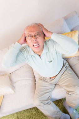 Oturma odasında başı ağrıyan yaşlı Asyalı adamın portresi.. 