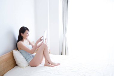 Yatak odasında dijital tablet kullanan kadın