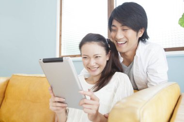 Genç mutlu çift evde tablet bilgisayar kullanıyor.