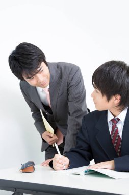 Asyalı erkek öğretmen derste öğrenciye yardım ediyor 