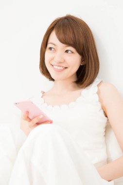 Gülümseyen güzel Japon kadın akıllı telefon kullanıyor.