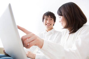 Bir adam ve bir kadın kanepede oturup laptopa bakıyorlar.