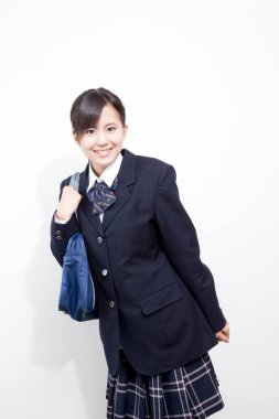 Okul üniformalı, çantalı genç Japon kızın stüdyo portresi.