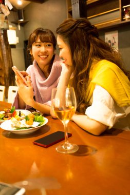 Genç Japon kadınları barda şarap içiyor.