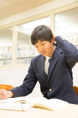 Asyalı öğrenci kütüphanede okuyor.