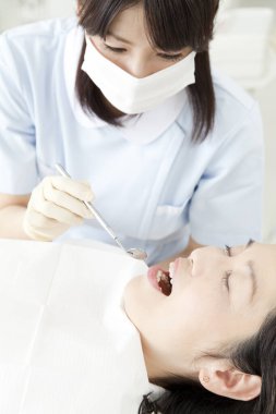 Asyalı kadın klinikte dişçiyi ziyaret ediyor