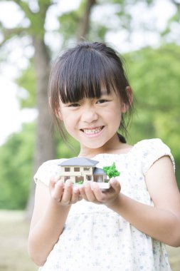 Asyalı kız ev modelini tutuyor. 