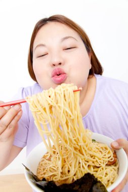 Şişman Asyalı kadın erişte yiyor. Stüdyo resmi