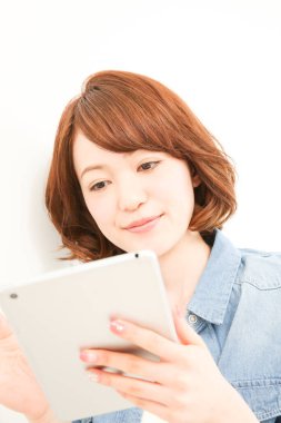 Dijital tablet kullanan gülümseyen Asyalı kadın