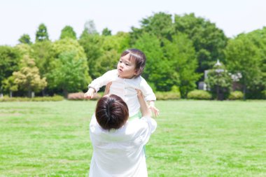 Mutlu Asyalı genç anne ve küçük oğlu parkta oynuyorlar.